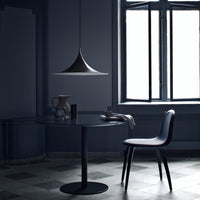 Modern black table and chair, sleek design with a subtle gray patterned floor in a dark, moody setting.
