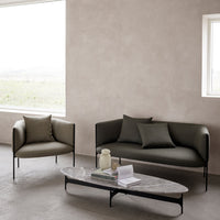 Modern sofa and chair set in muted olive green with black metal frames, complemented by a sleek marble coffee table.