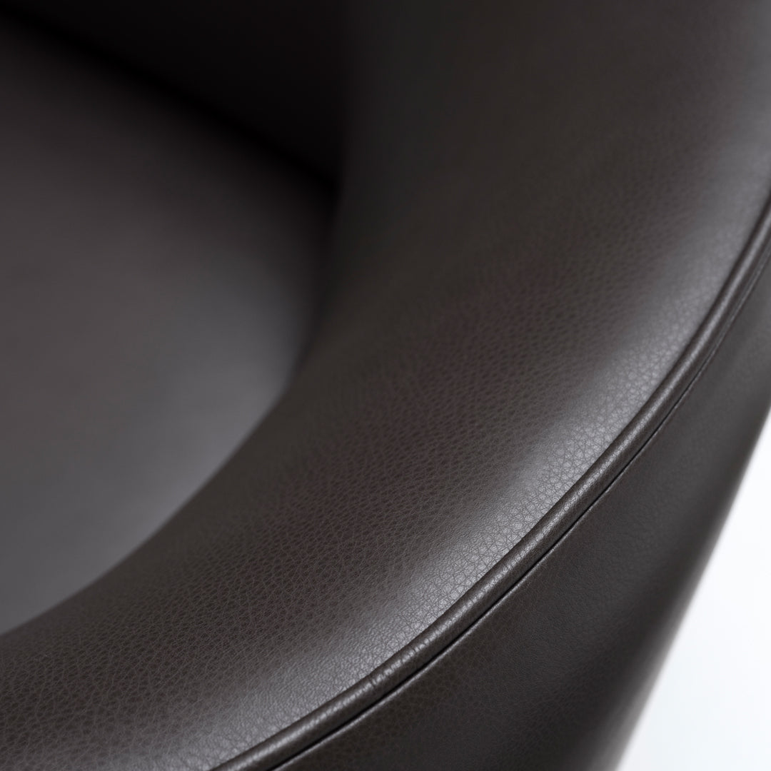 Dark brown, smooth leather upholstery with subtle texture and sleek curved edges, ideal for modern decor.