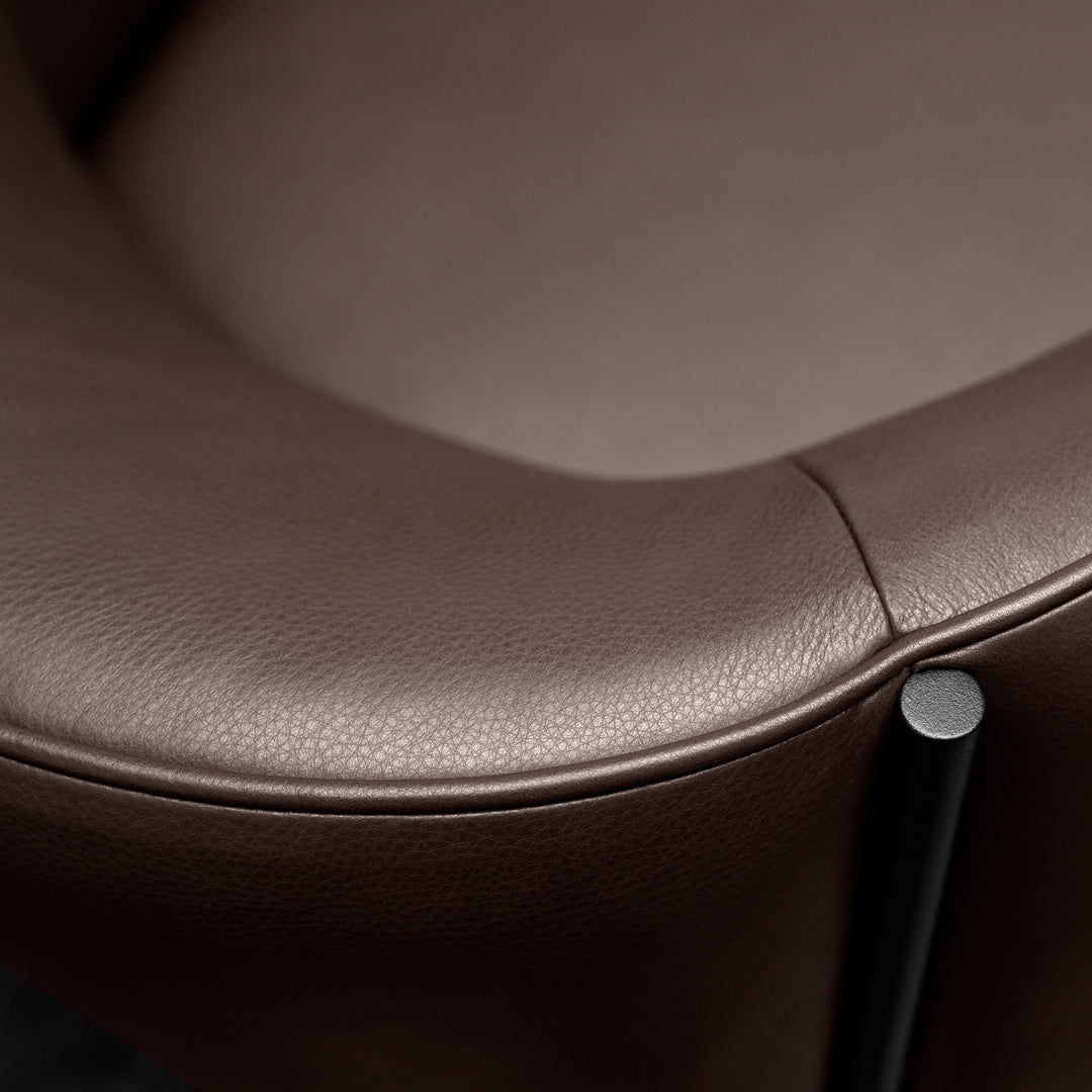 Close-up of a brown leather chair featuring smooth texture and sleek black metal accents. Perfect for modern decor.