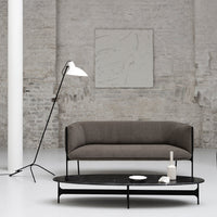 Modern gray sofa with a smooth texture and black coffee table in a minimalist, neutral-toned interior.