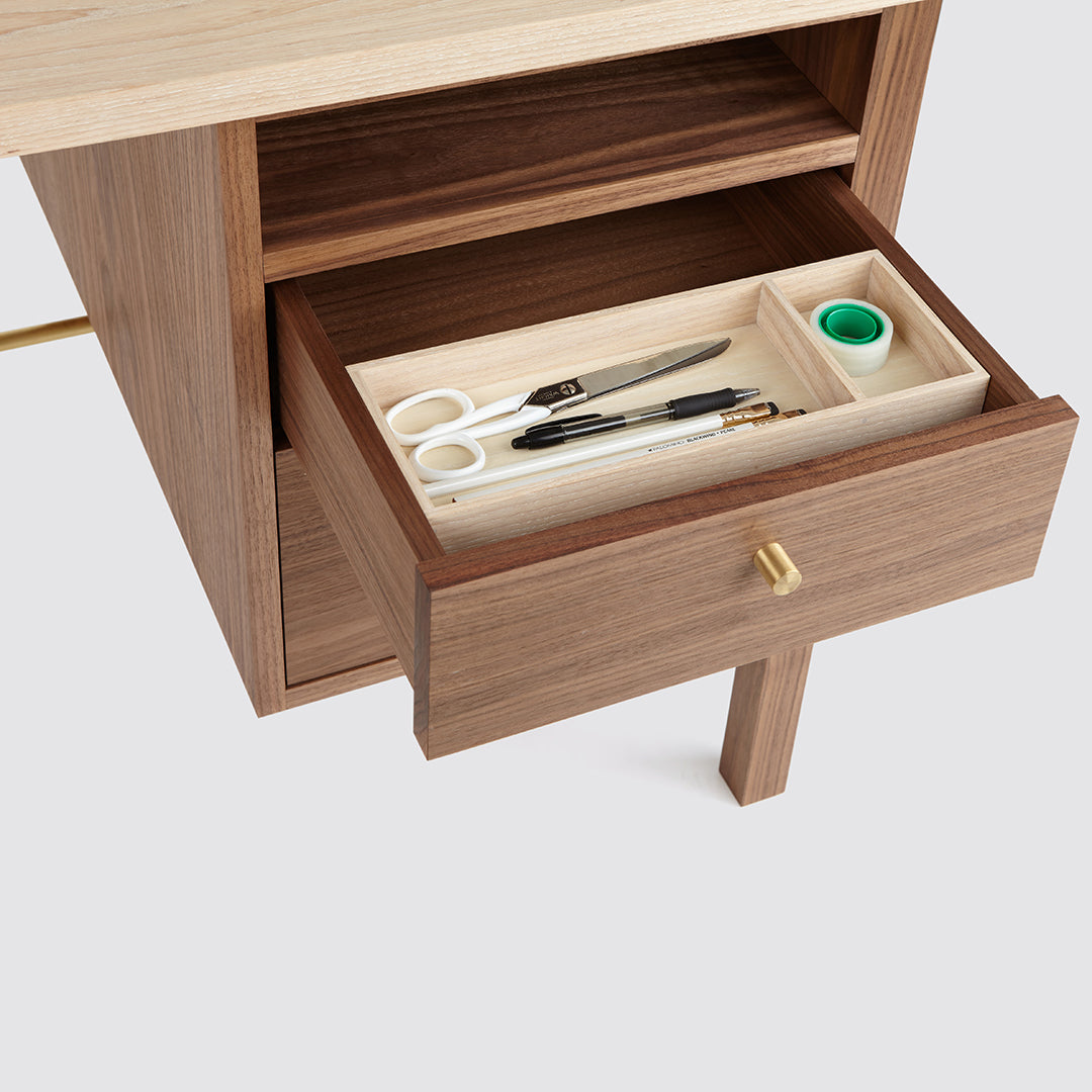 "Close-up of walnut drawer with cream interior, featuring organized tools and a sleek gold knob."