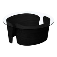 Black sculptural coffee table with a clear glass top, featuring smooth, modern curves and a minimalist design.