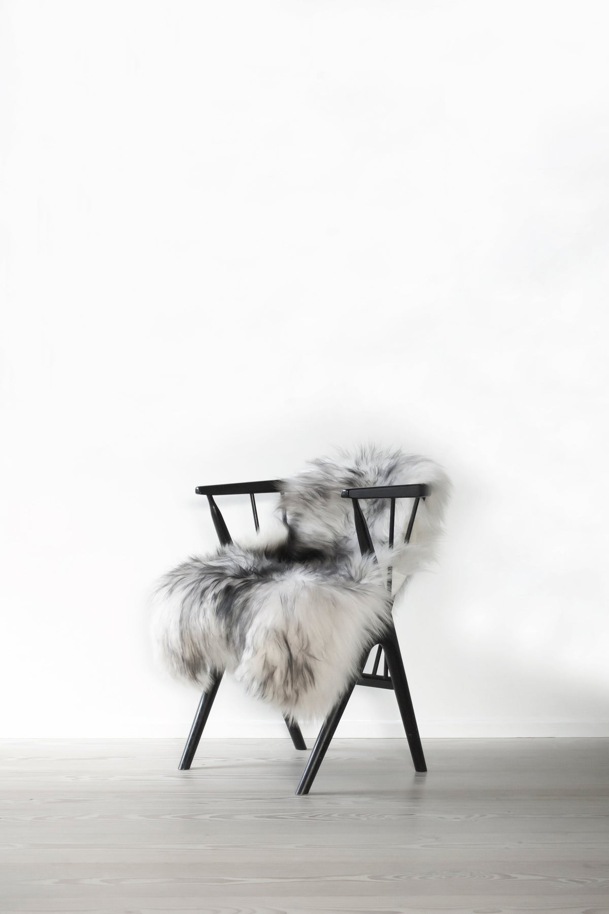 Black chair with gray and white faux fur, featuring a minimalist design and soft texture. Ideal for modern decor.