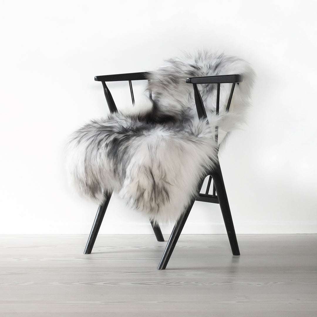 Black wooden chair with plush gray and white fur, featuring a modern, stylish pattern and soft texture.
