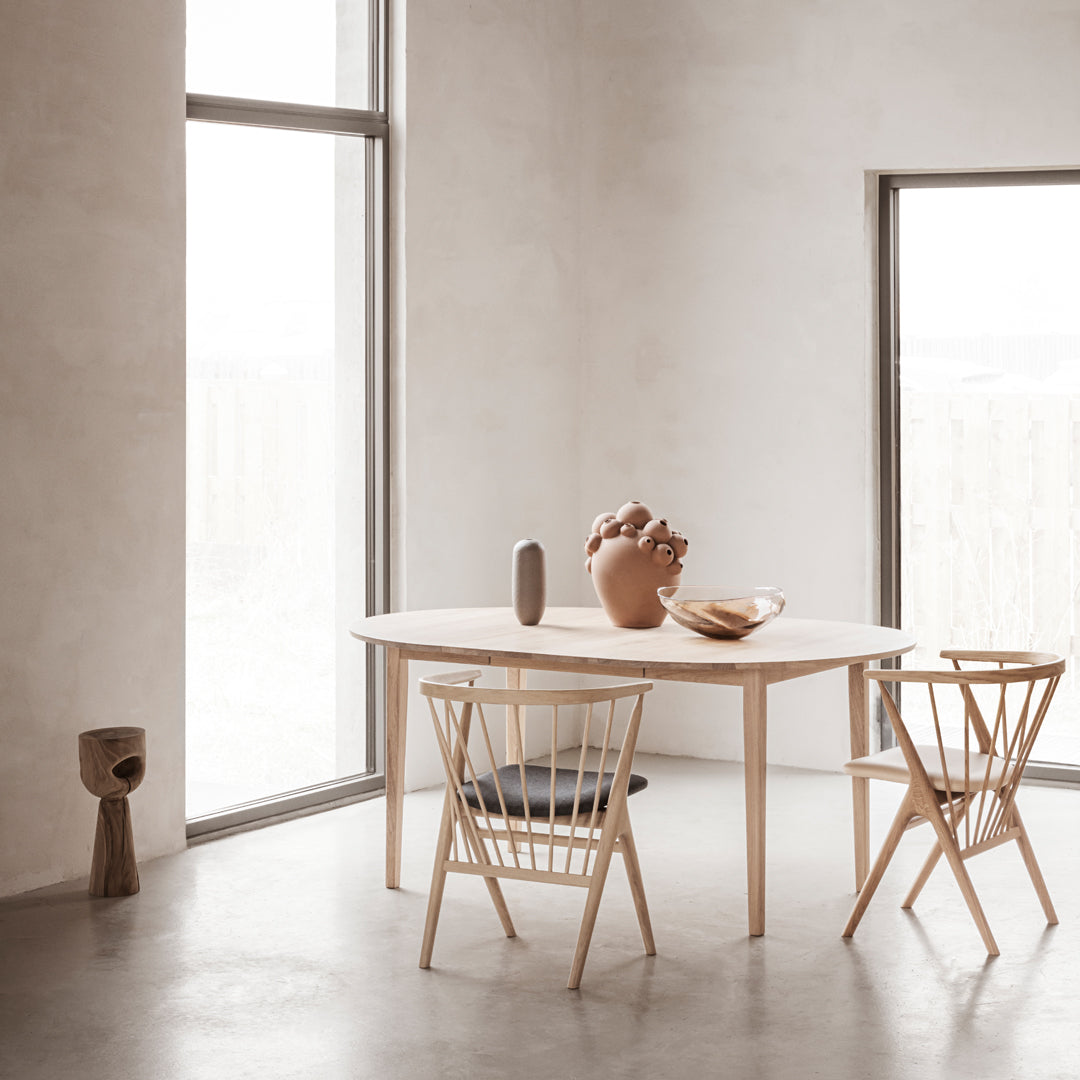Light wood dining table with minimalist design, complemented by cream walls and natural earthy accents in decor.