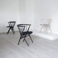 Set of three modern chairs: one black, one white, each showcasing a sleek, minimalist design and wooden finish.