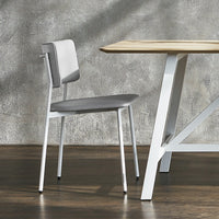 Gray chair with a sleek, minimalist design, paired with a light wood table against a textured gray wall.