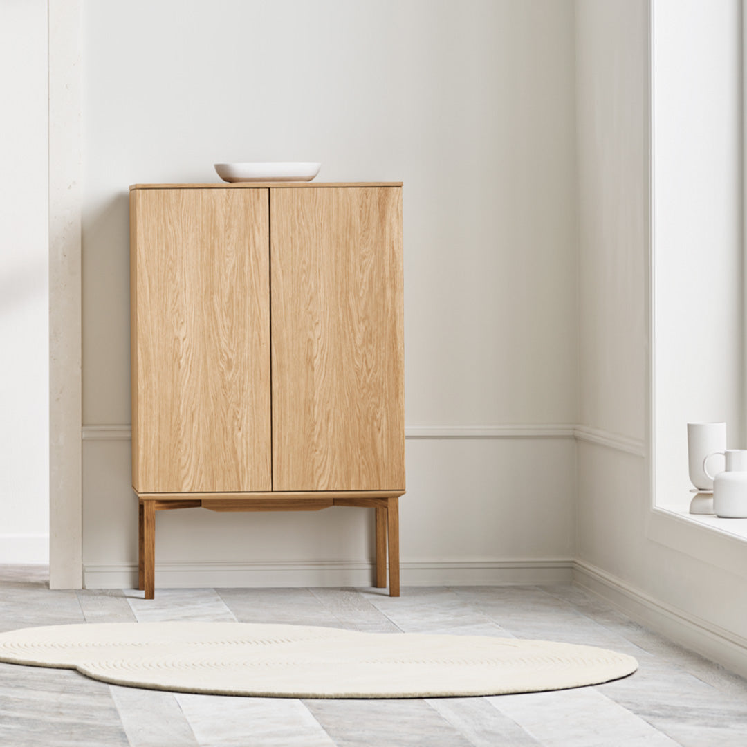 Light wood cabinet with a smooth finish against a neutral wall, paired with a soft cream rug.