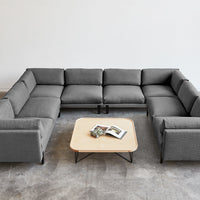 Gray sectional sofa with modern design, featuring smooth upholstery and contrasting black metal legs, paired with a light table.