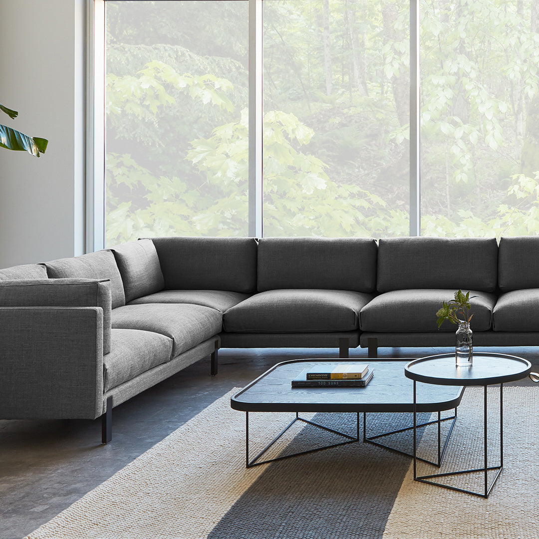 Gray sectional sofa with sleek lines, complemented by a geometric accent table on a soft, striped area rug.