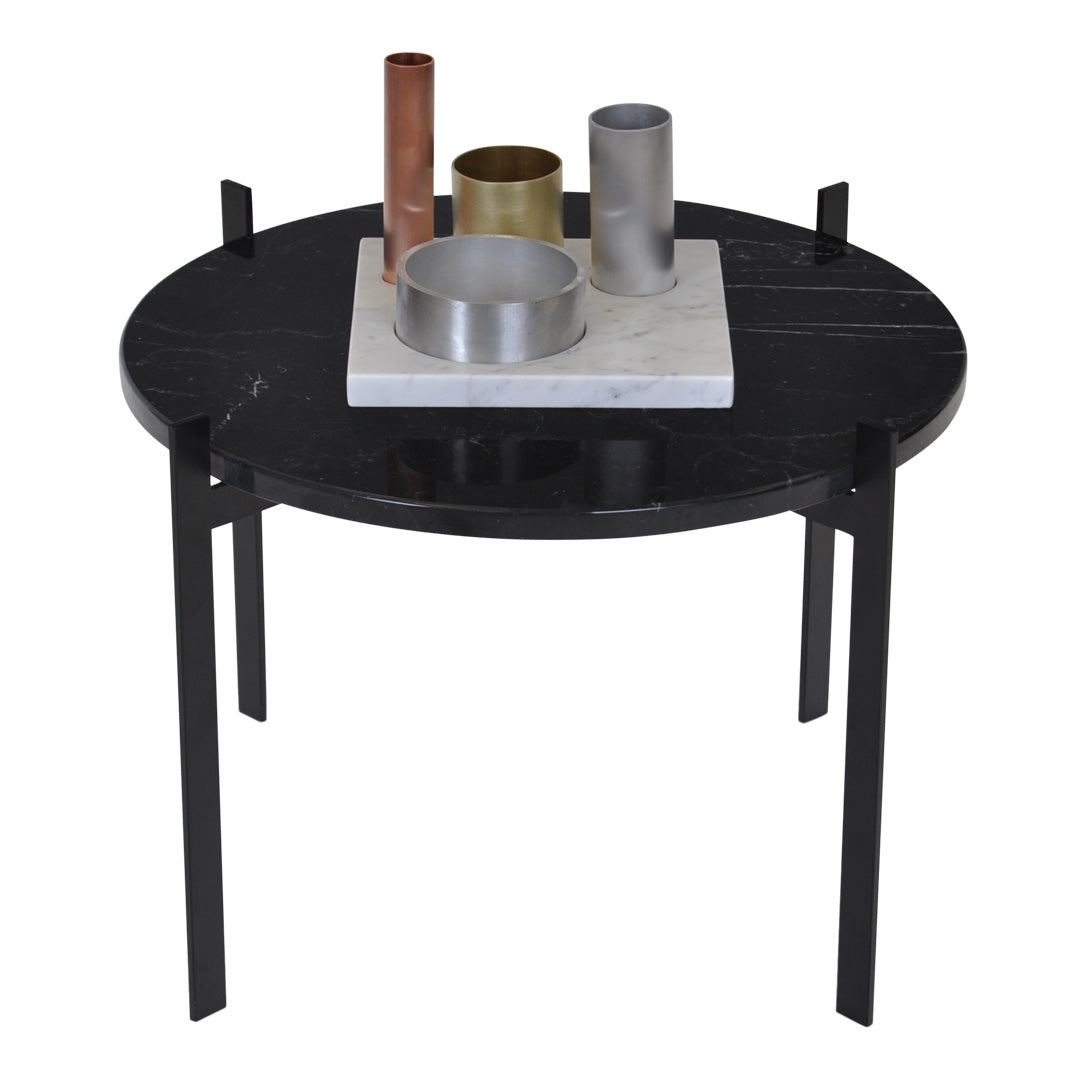 Round black marble side table with sleek black legs, featuring a mix of metallic silver, gold, and copper decorative items.