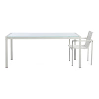 Sleek white metal table with a clear glass top and minimalist chair, featuring a modern and elegant design.
