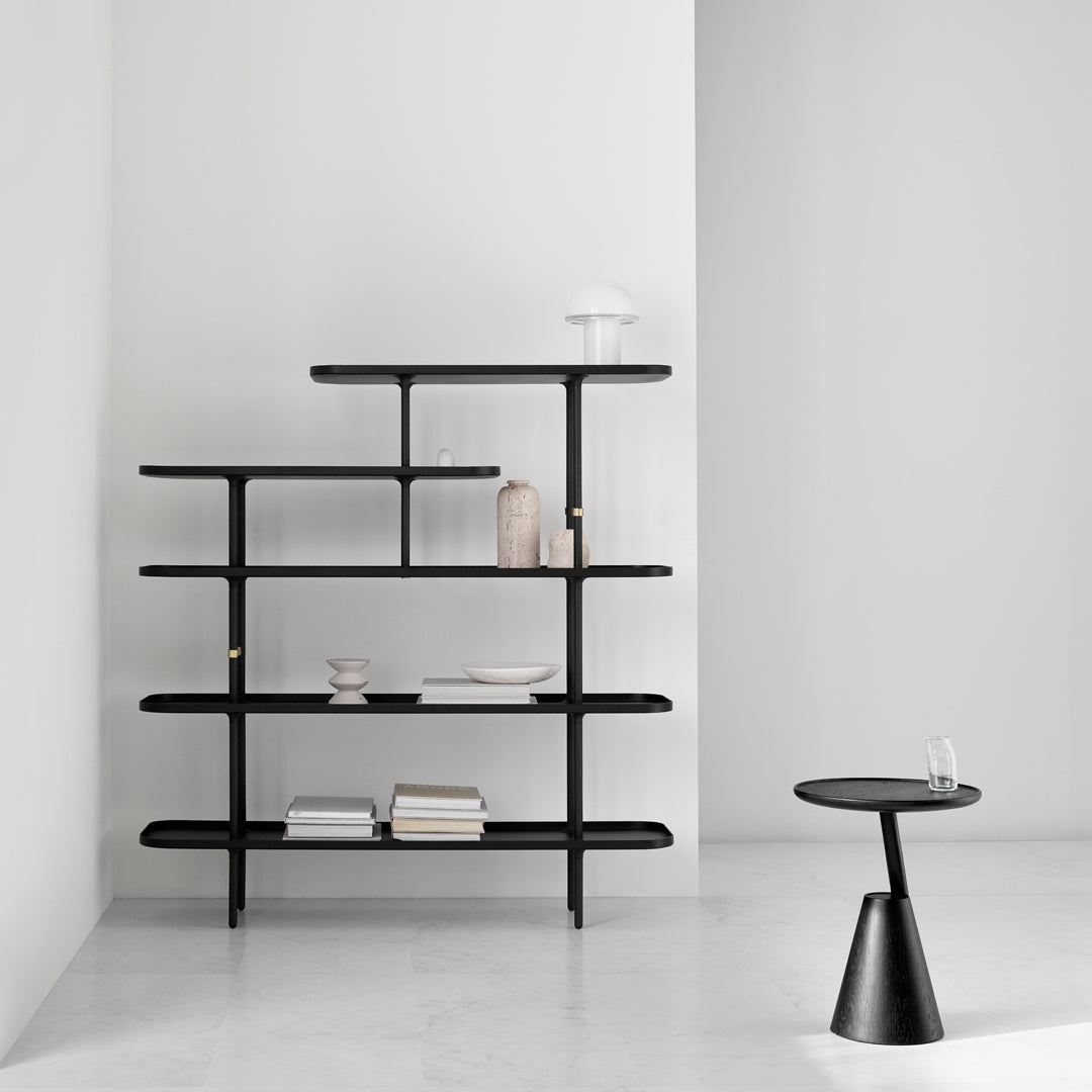 Black multi-tiered bookshelf against a minimalist white wall, with various decorative items on shelves.