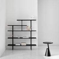 Black multi-tiered bookshelf against a minimalist white wall, with various decorative items on shelves.