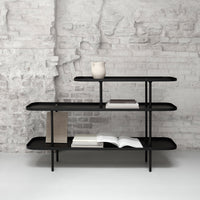 Sleek black shelf with minimalist design, set against a textured gray brick wall.