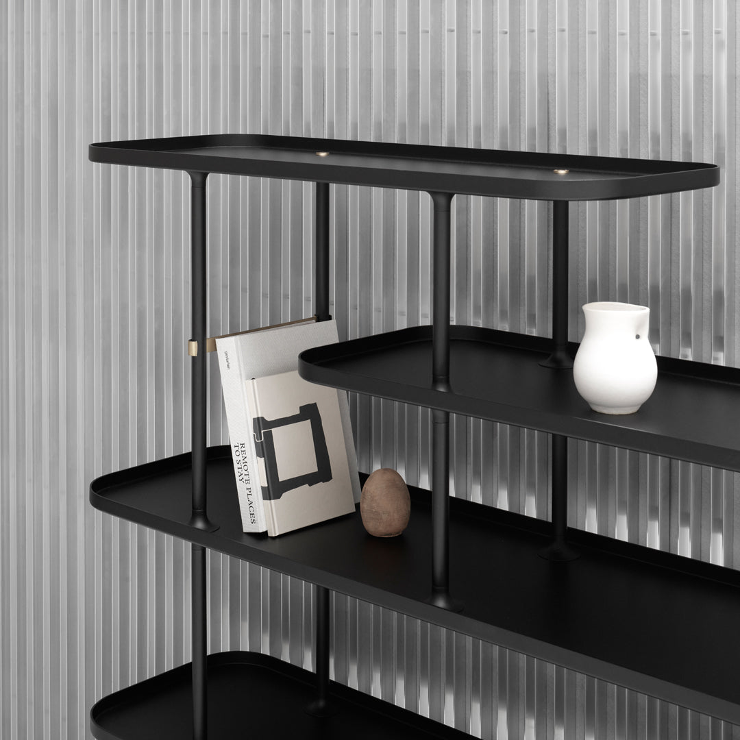 Sleek black shelving unit with smooth surfaces, minimalist design, and a subtle vertical striped background.