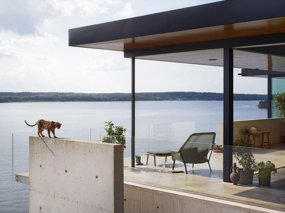 Modern patio featuring a mix of gray, green, and wood tones against a scenic blue water backdrop.
