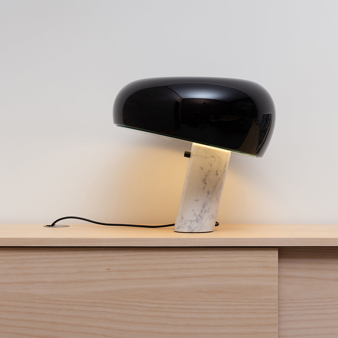 Black and white marble table lamp with a sleek, modern design and soft, warm light glowing from the base.
