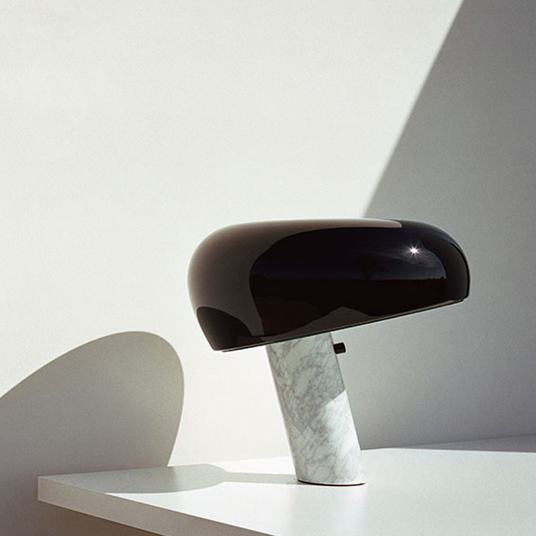 Black glossy lamp with a smooth, rounded shade and a white marble base, featuring clean lines and modern design.