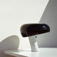 Black glossy lamp with a smooth, rounded shade and a white marble base, featuring clean lines and modern design.