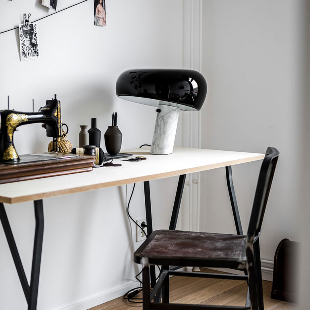 Black and white lamp on a modern workspace with wood and metal accents, featuring minimalist design elements.
