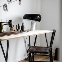 Black and white lamp on a modern workspace with wood and metal accents, featuring minimalist design elements.