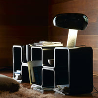 Modern black storage unit with white outlines, featuring geometric patterns and a sleek black lamp for stylish decor.