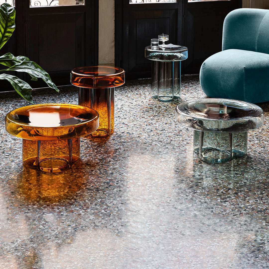 Glass tables in amber, teal, and clear colors; contemporary design with smooth, glossy finishes. Perfect for modern decor.
