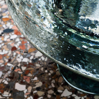 Clear turquoise glass bowl reflecting colorful speckled terrazzo pattern underneath. Modern and stylish design.