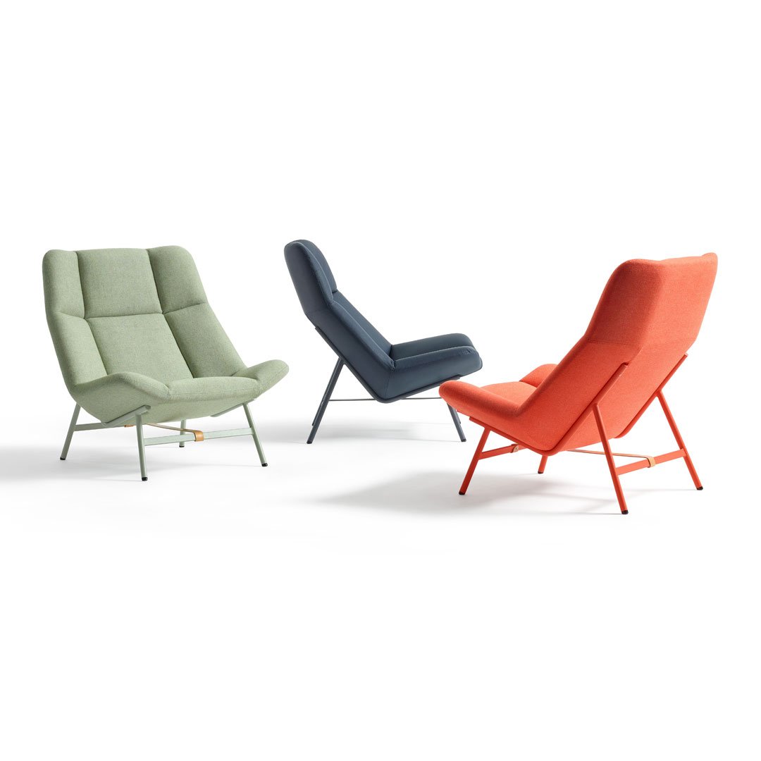 Modern armchairs in soft green, deep navy, and vibrant coral upholstery with sleek metal legs.
