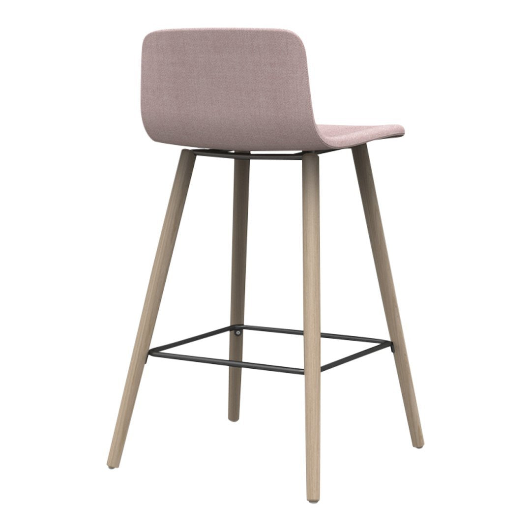 Pink upholstered stool with natural wood legs and a sleek black metal footrest, featuring a minimalist design.