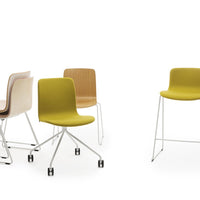 Colorful modern chairs in vibrant yellow, soft pink, warm wood tones, and sleek white metal frames.