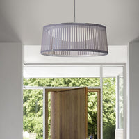 Gray striped pendant light casting soft shadows in a modern entryway with natural greenery in the background.