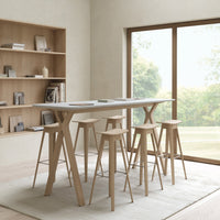 Scandinavian-style bar table with a white top and natural wood legs, complemented by neutral-colored stools.