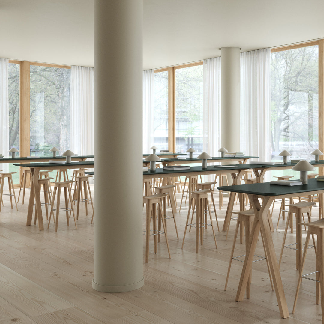 "Modern dining space with light wood floors, natural light, white curtains, and minimalist black tabletops."