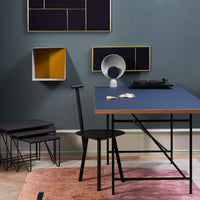 Modern black and navy dining set with geometric wall art in gray and yellow tones, featuring a soft pink area rug.