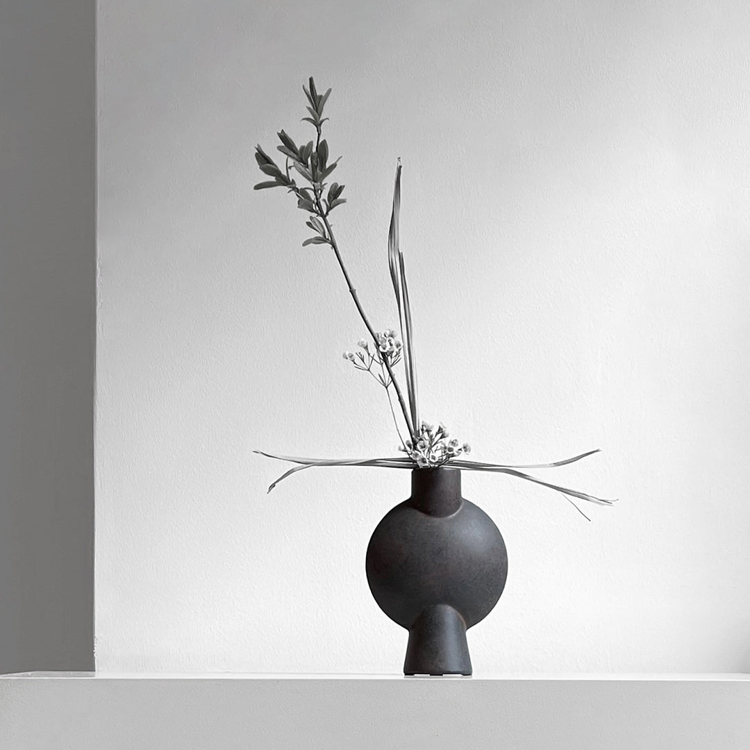 Black ceramic vase with a textured base, featuring a smooth, round body and minimalist design against a neutral backdrop.