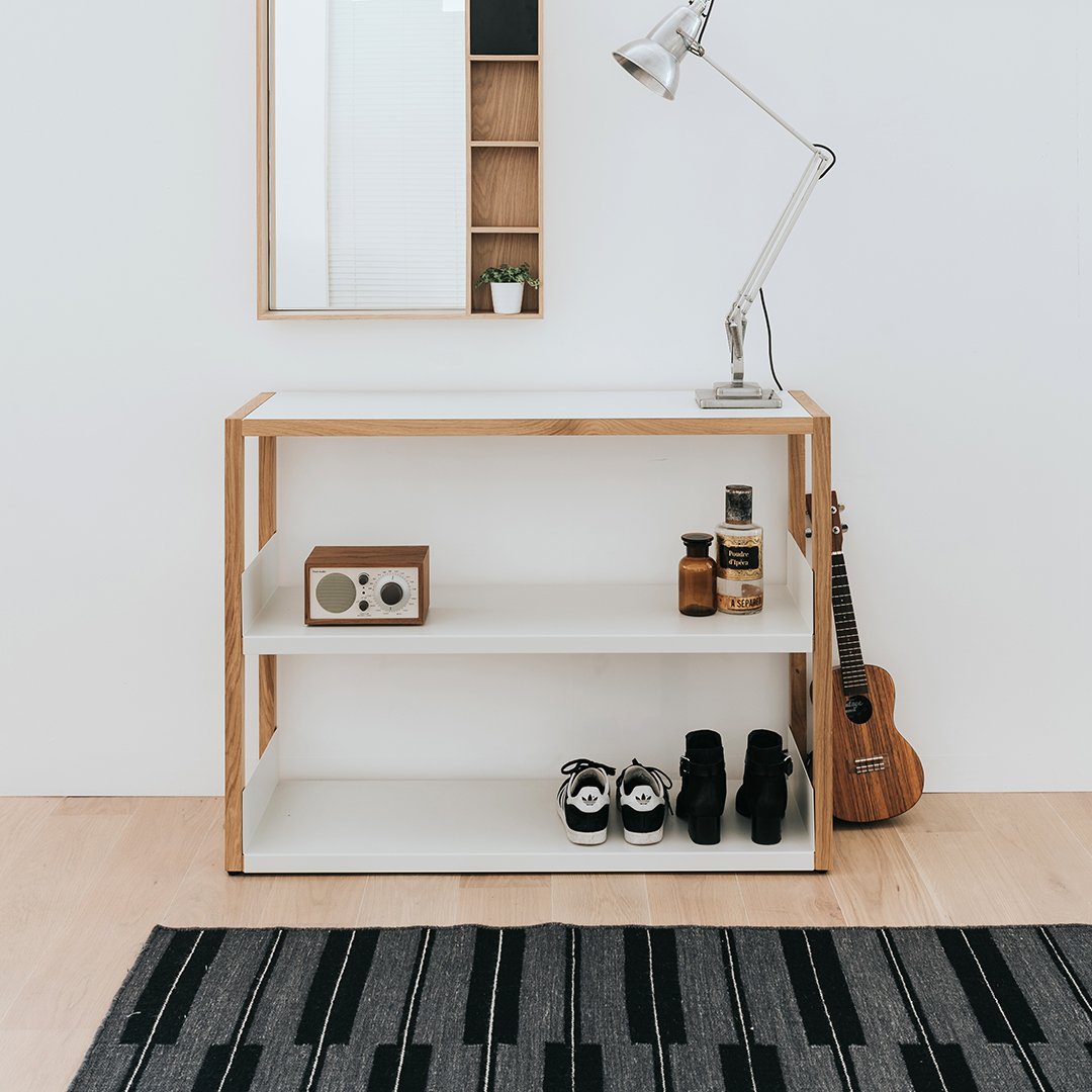 Modern wood console table with white shelves and a black and gray striped rug. Minimalistic design adds elegance.