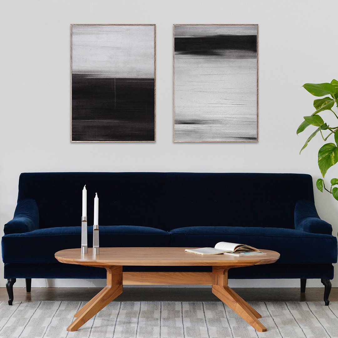 "Abstract black and white wall art featuring subtle textured patterns above a deep blue velvet sofa and wooden coffee table."