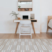 Neutral-toned rug with a striped pattern in shades of beige and gray, enhancing a minimalist workspace aesthetic.