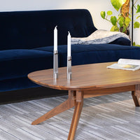Navy blue velvet sofa beside a wooden coffee table with light wood grains and two silver candle holders.