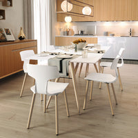 Modern white dining chairs with light wooden legs, set against a sleek, neutral-toned kitchen backdrop.