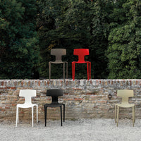 Vibrant modern chairs in red, cream, black, brown, and olive green against a rustic stone wall backdrop.