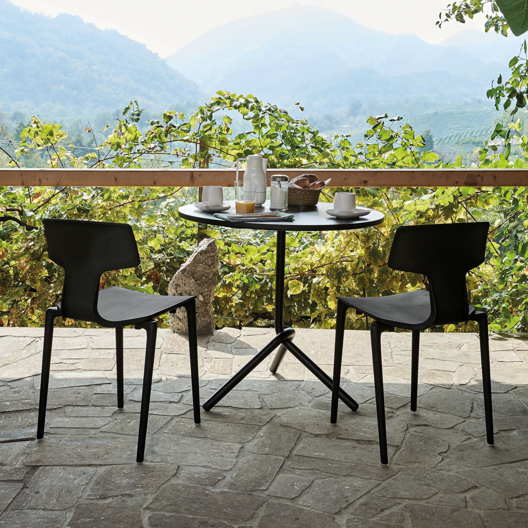 Black and gray dining chairs paired with a round black table, set against a serene mountain backdrop.