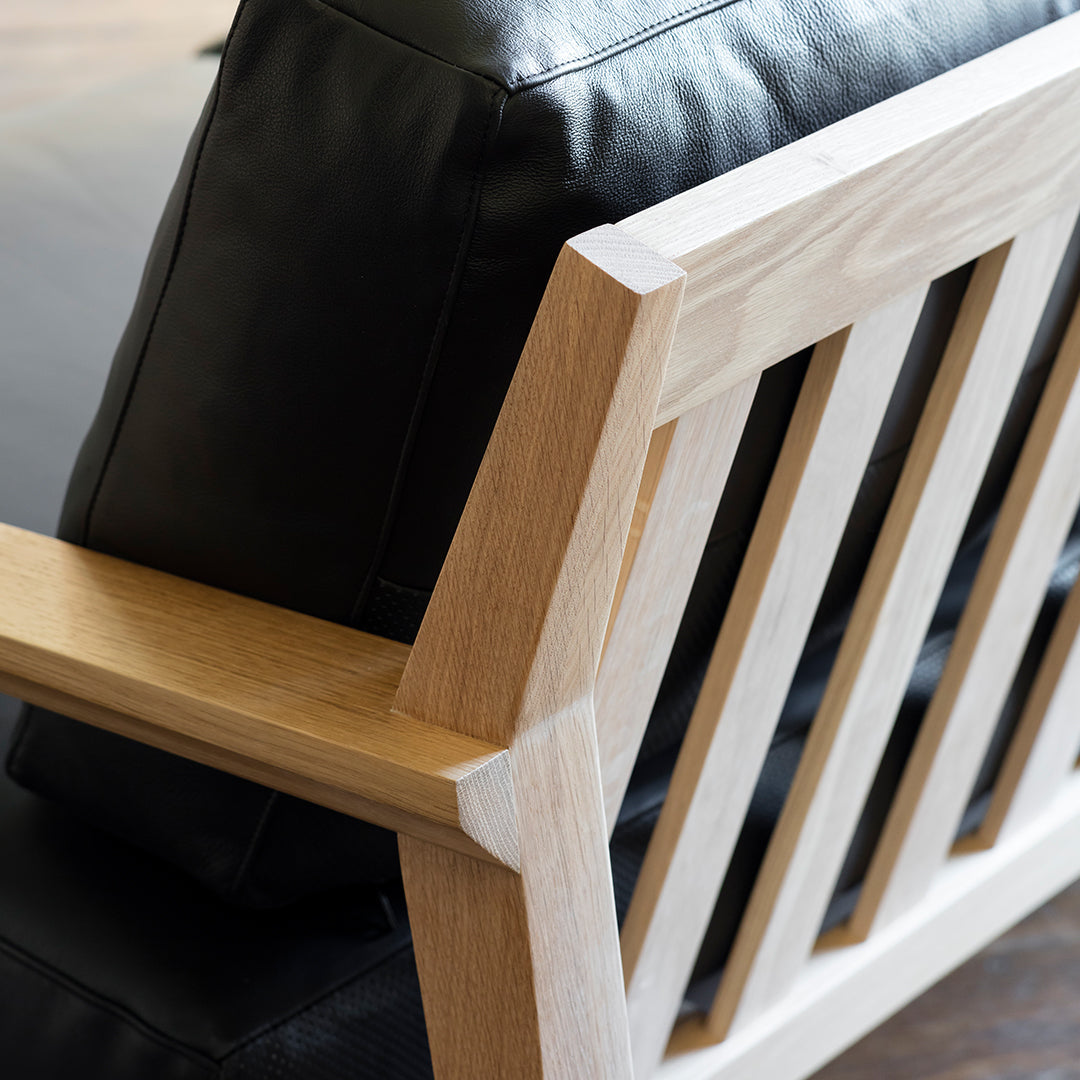 Black leather sofa with a natural wood frame featuring a slatted design and smooth finishes.