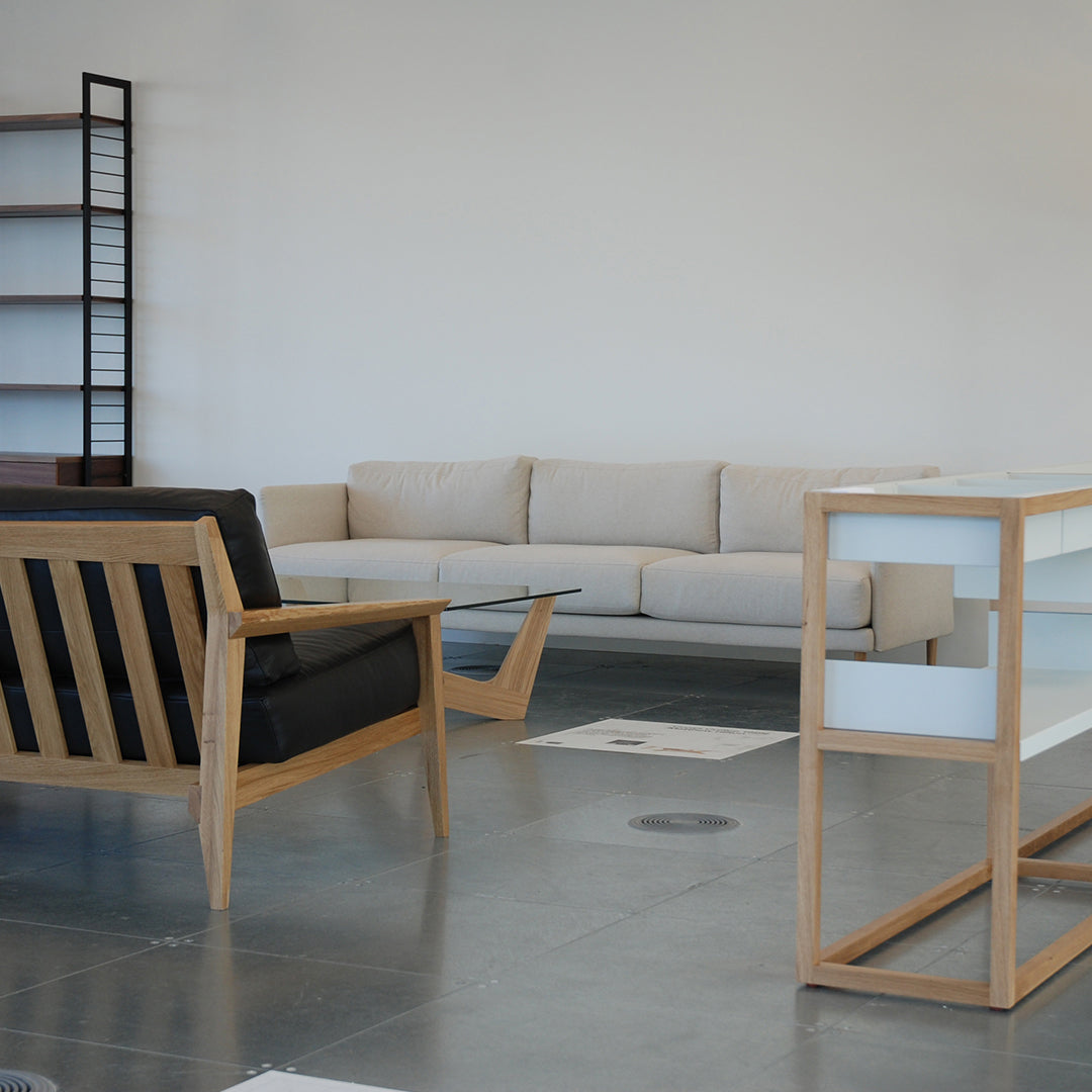 Modern beige sofa, black and natural wood armchair, sleek white and wood side table, minimalist decor layout.