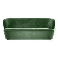 Velvet green sofa with a smooth, modern design and a rounded backrest, perfect for stylish living spaces.