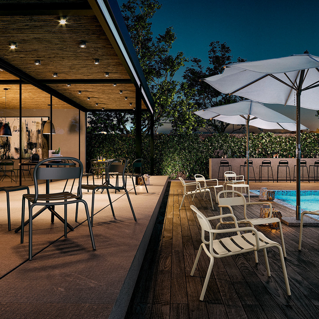 Elegant outdoor seating in muted gray and cream tones, paired with a vibrant pool and lush green backdrop.