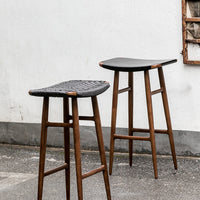 Black woven bar stools with natural wood legs, featuring sleek, modern design and textured patterns.
